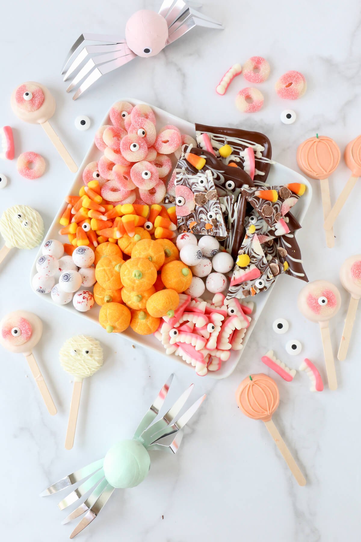 A white platter filled with orange and pink halloween candy.  