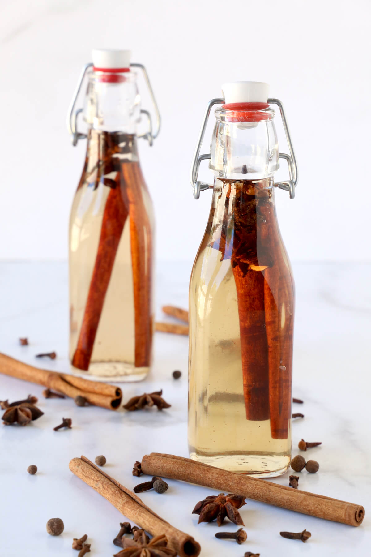 Two jars of simple syrup, filled with cinnamon sticks, anise and cloves.