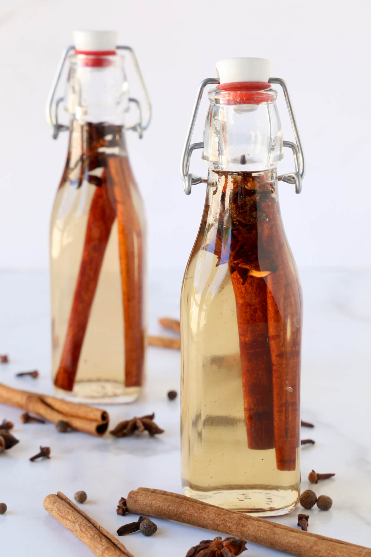 Two jars of simple syrup, filled with cinnamon sticks, anise and cloves.