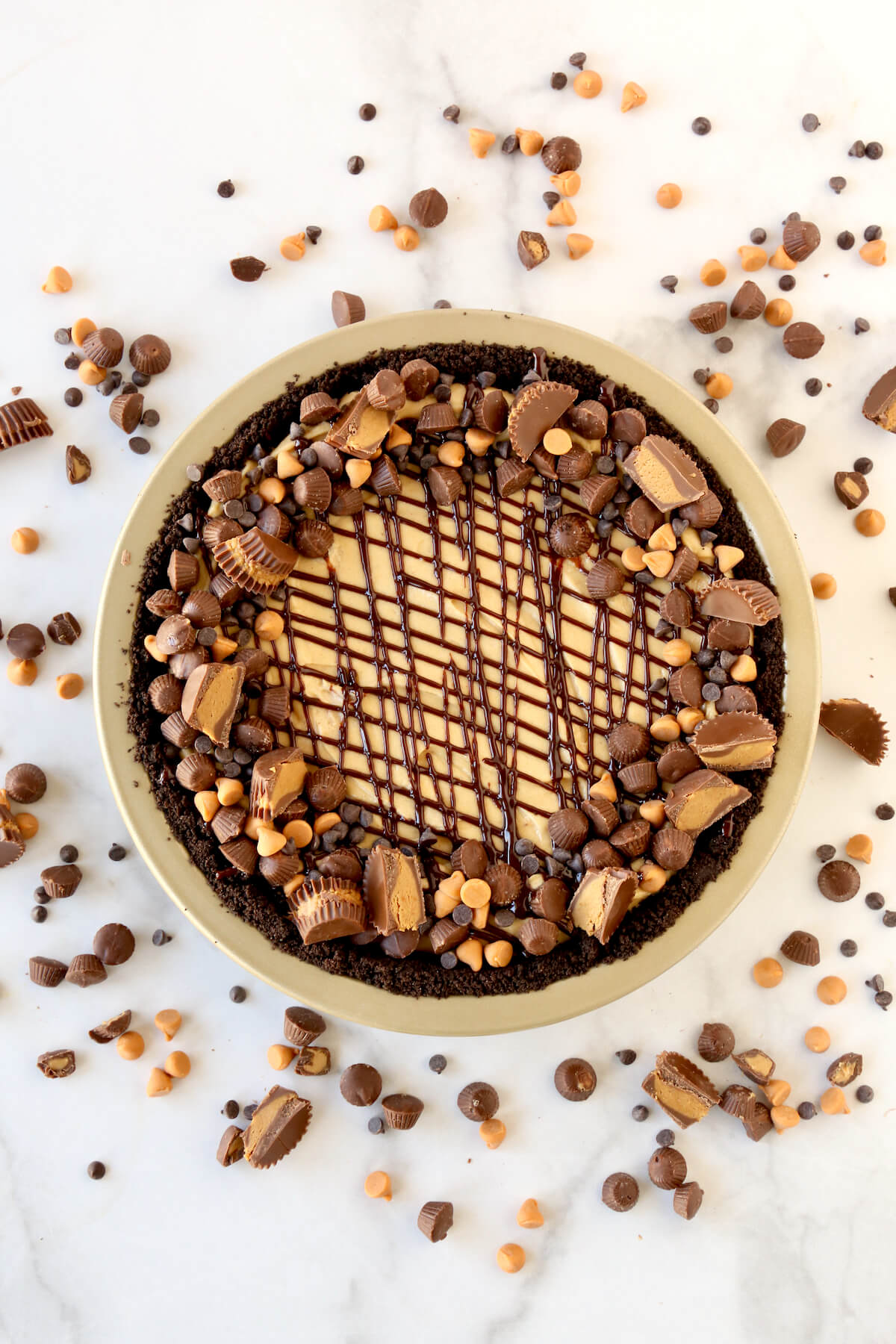 A round pie with chocolate crust, peanut butter filling and reeses candies covering the top and surrounding the pie.  