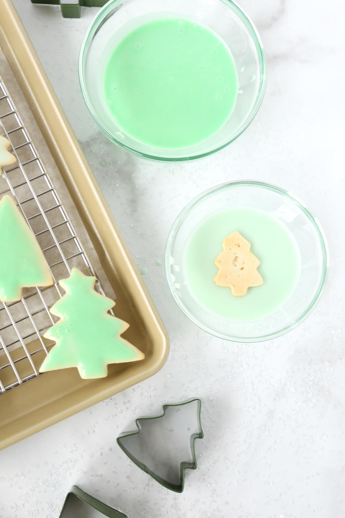 A close up of a gold tray with ice tree cookies and a tree dipped in green icing.