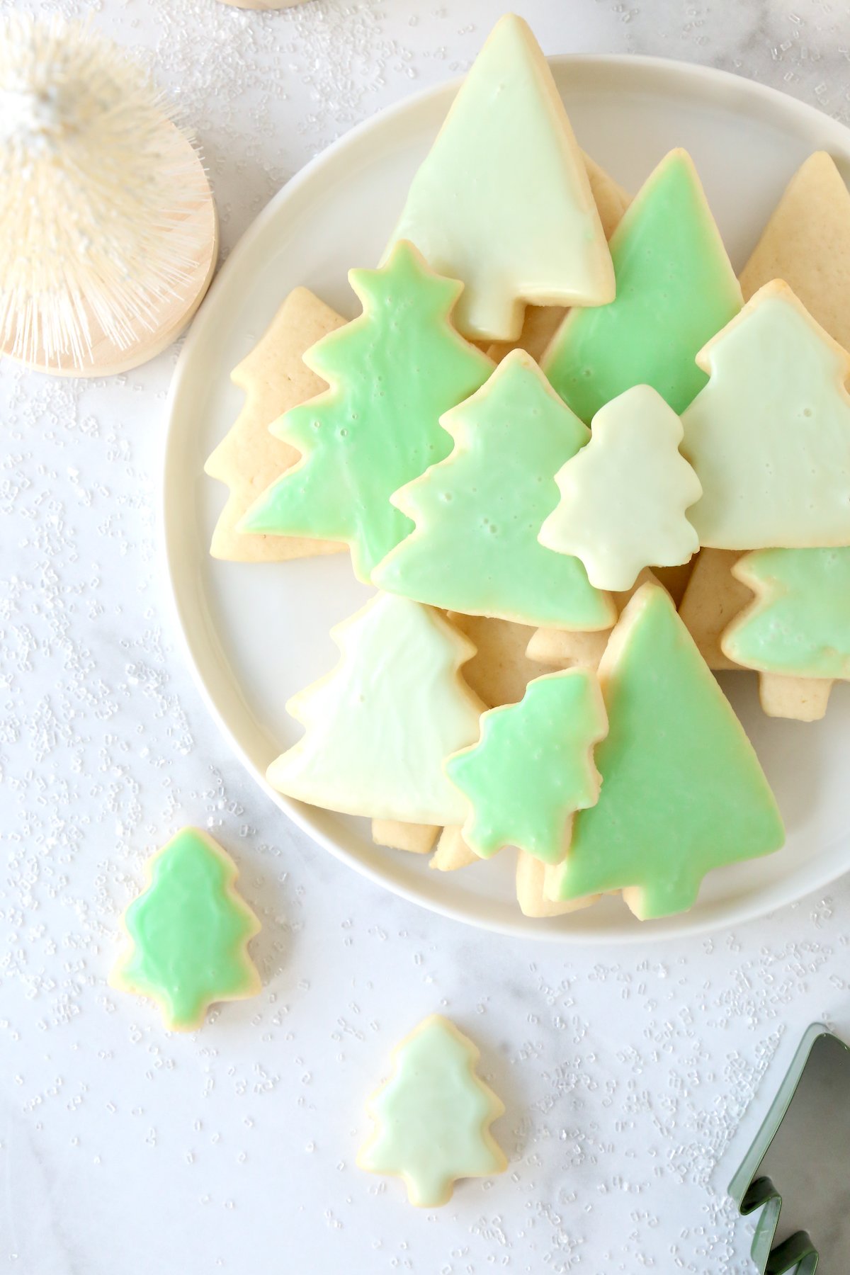 A white plate with green tree cookies. 