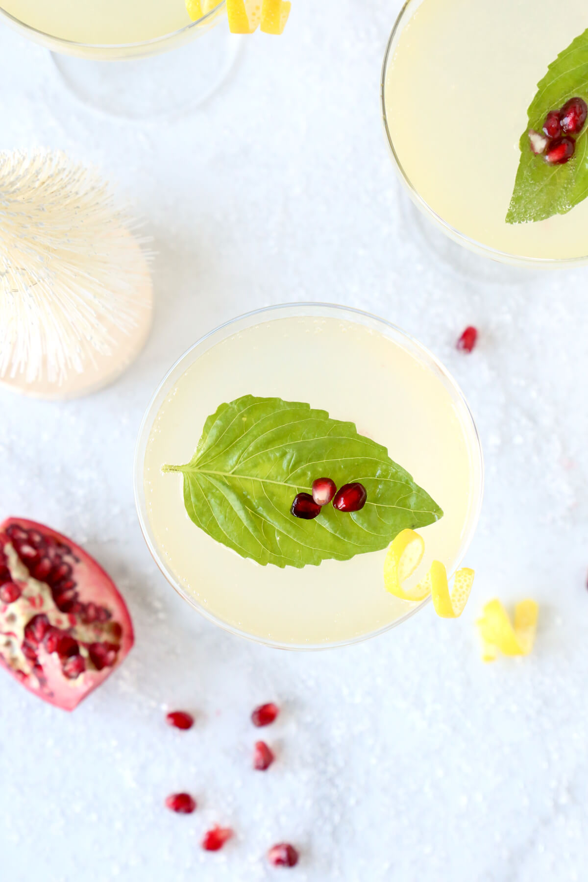 A clear glass with a basil leaf and three pomegranate seeds on top.  