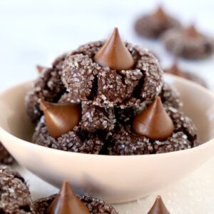 A pink bowl filled with chocolate cookies with chocolate kisses on top.