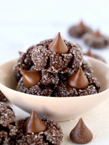 A pink bowl filled with chocolate cookies with chocolate kisses on top.