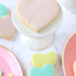 Pink heart plates with heart cookies and heart candies placed on them.
