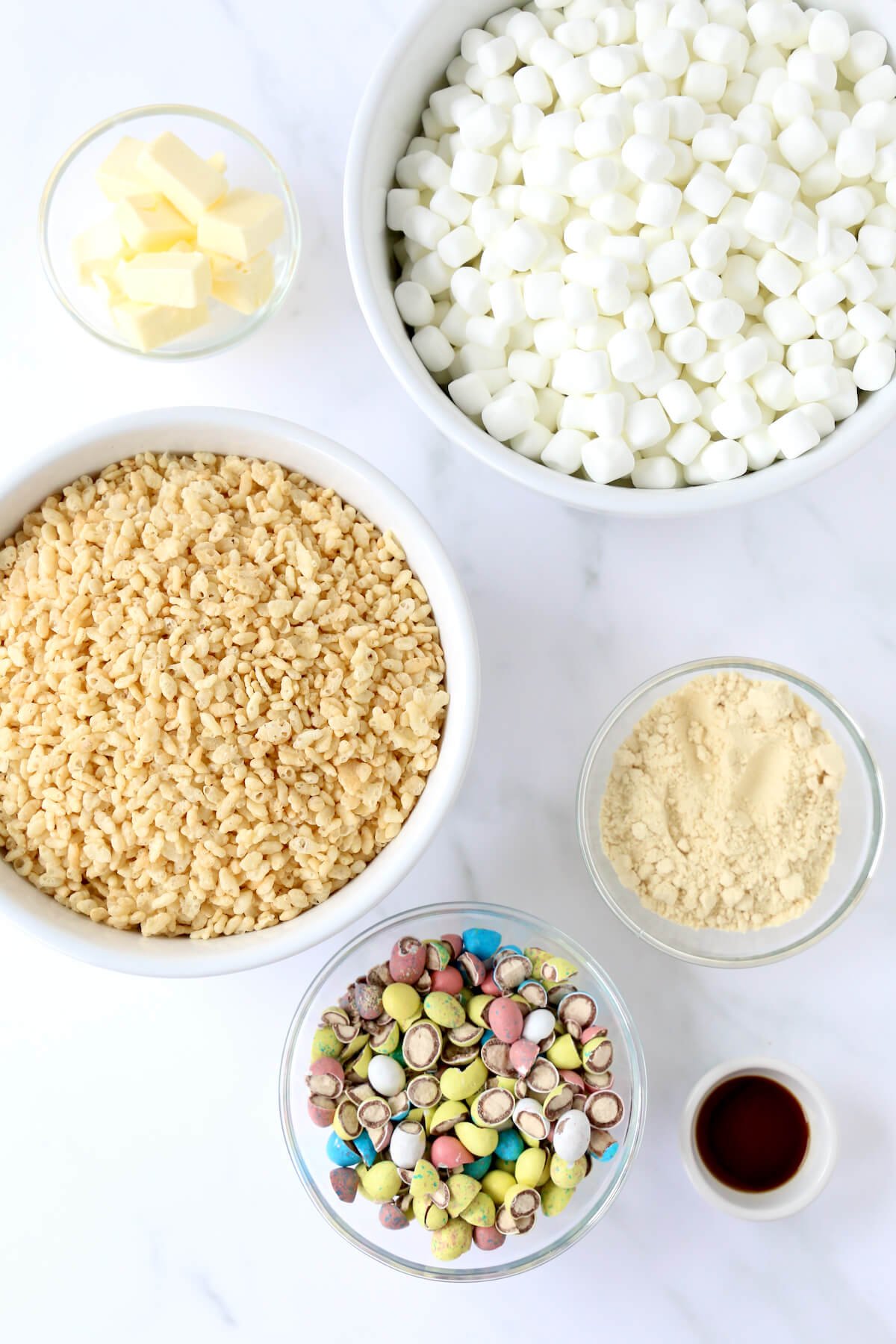 Bowls of mini marshmallows, rice Krispie cereal, butter cubed, malted milk powder, egg malted candies and vanilla extract. 
