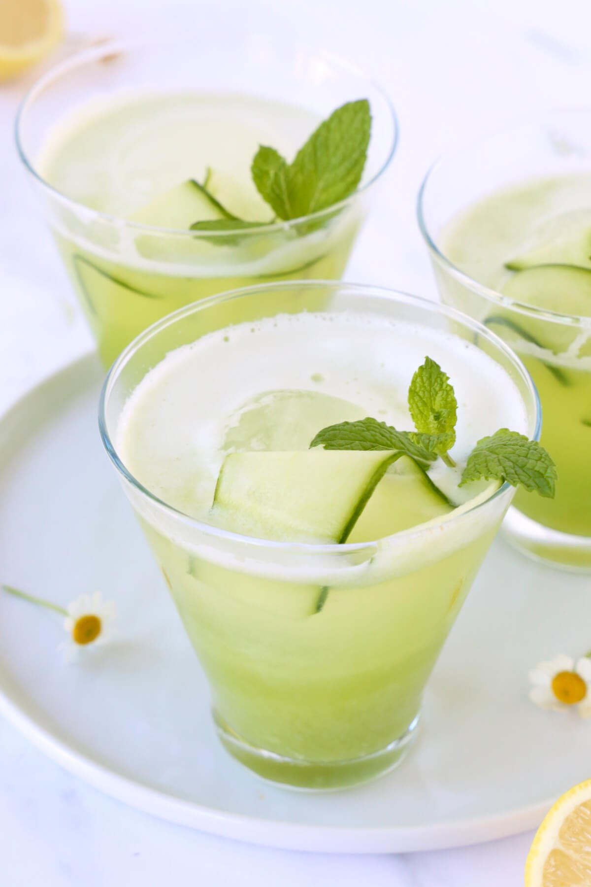 Three glasses filled with green liquid, cucumber and fresh mint.  