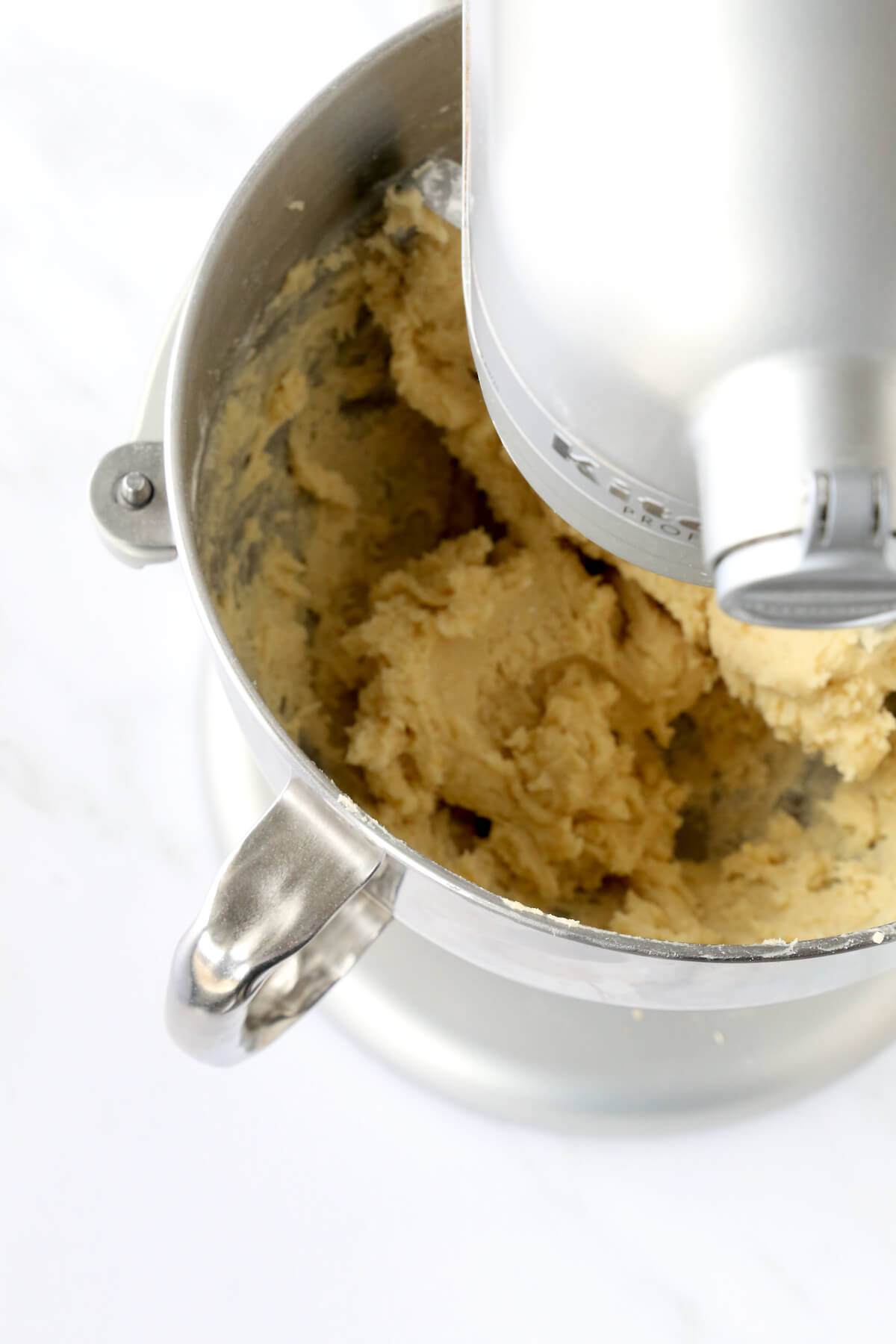 An electric mixer bowl filled with a cookie batter.
