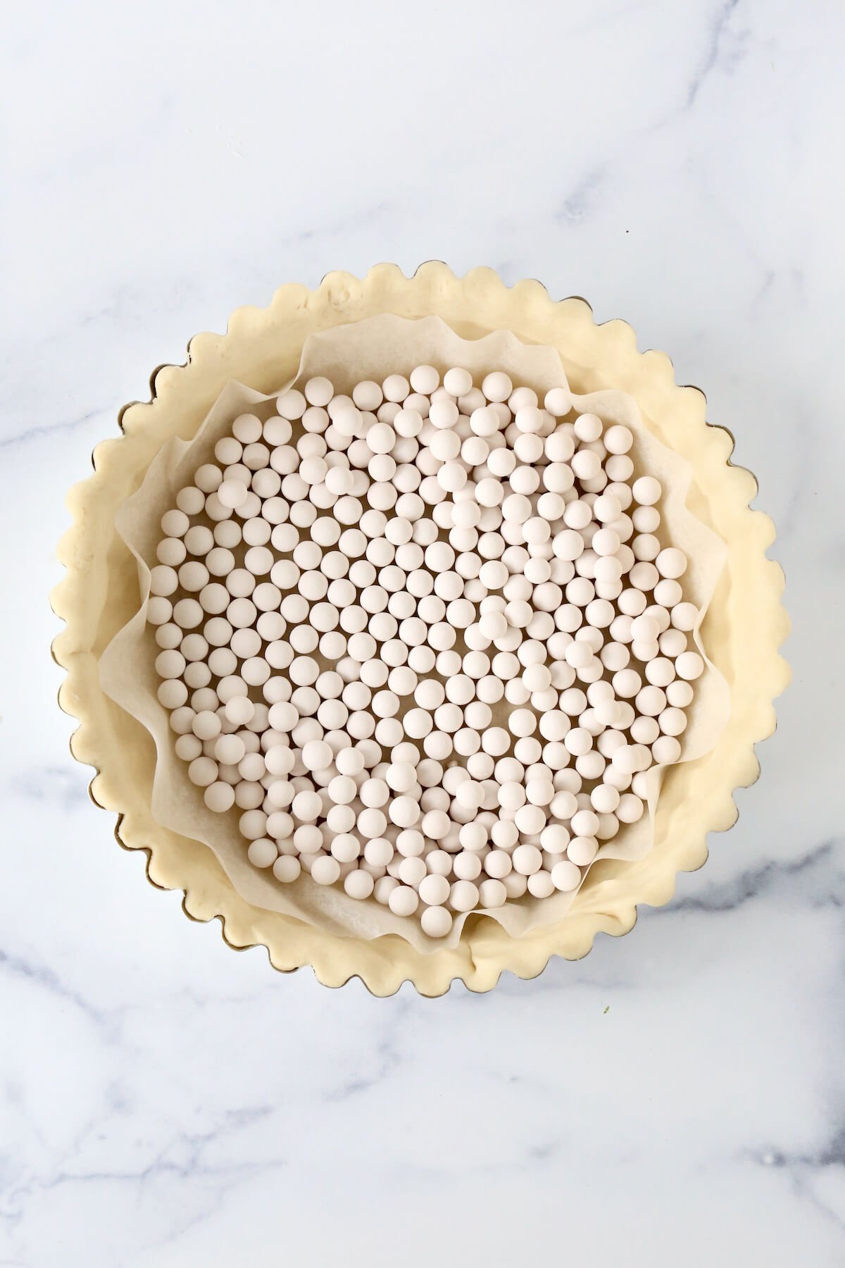 Pie dough in a deep dish tart pan filled with pie weights.