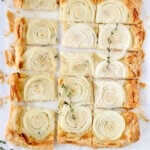 A puff pastry crust with sliced onions cut into squares.