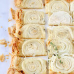 A puff pastry crust with sliced onions cut into squares.
