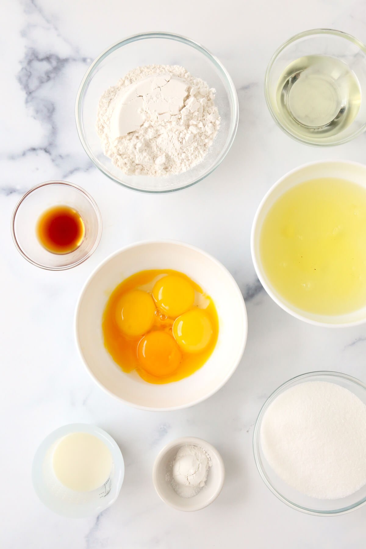 A bowl of egg yolks, egg whites, flour, sugar, vegetable oil, milk, and vanilla extract. 