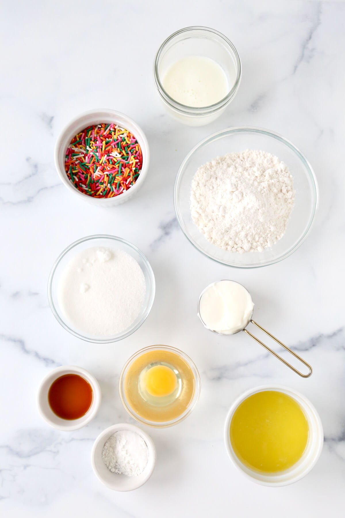 Bowls of flour, sugar, buttermilk, melted butter, one egg, vanilla extract and rainbow sprinkles.