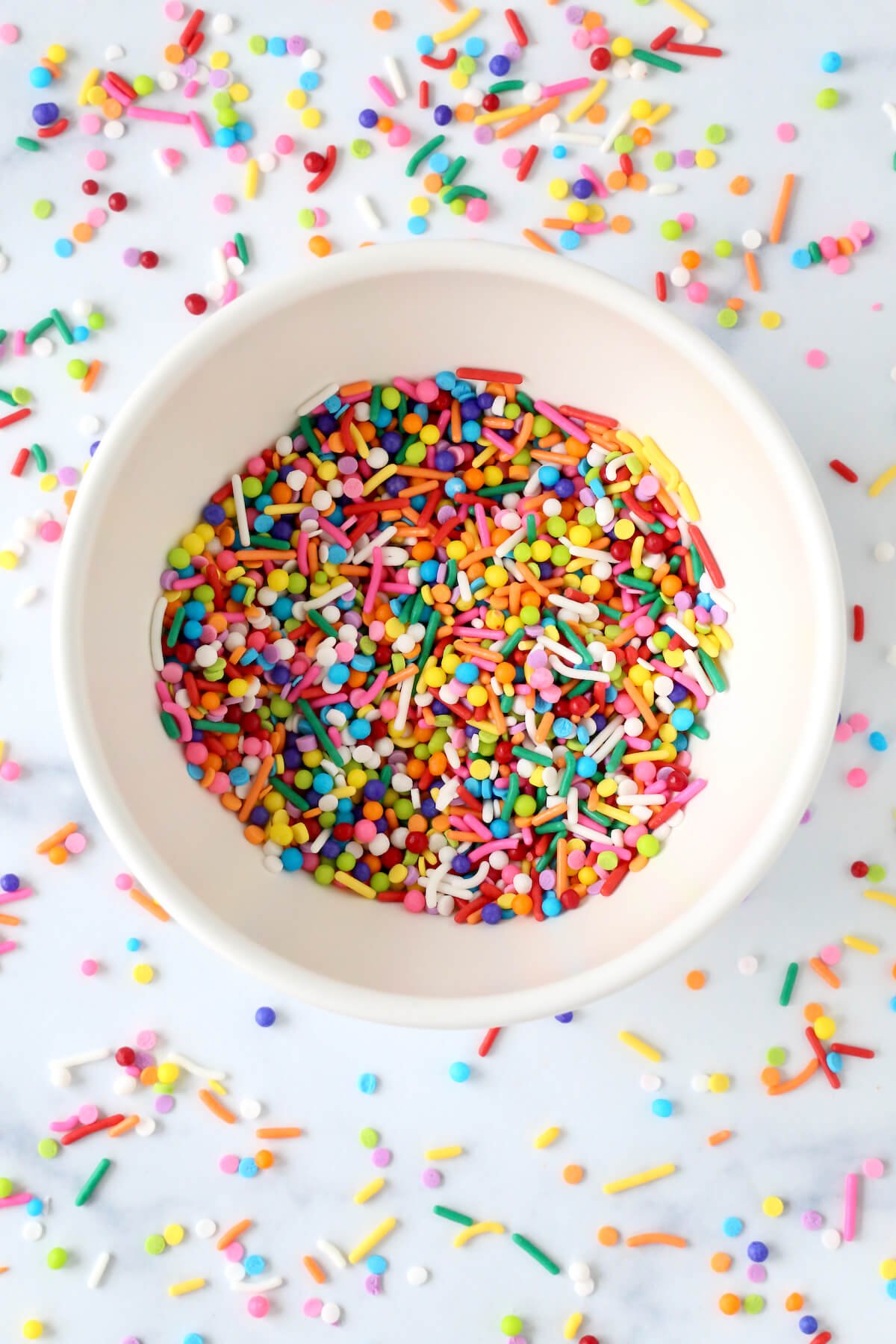 A white bowl filled with rainbow sprinkles.