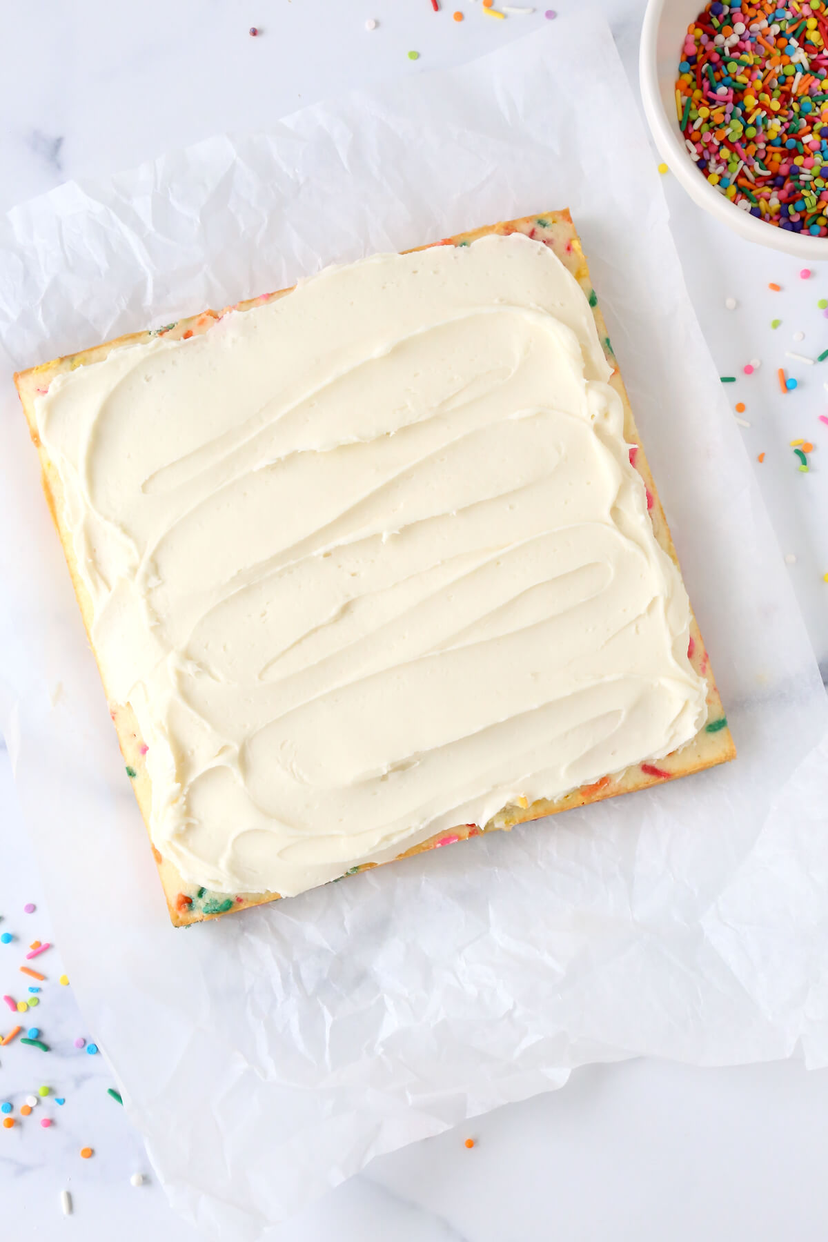 A square cake with white frosting spread on top.