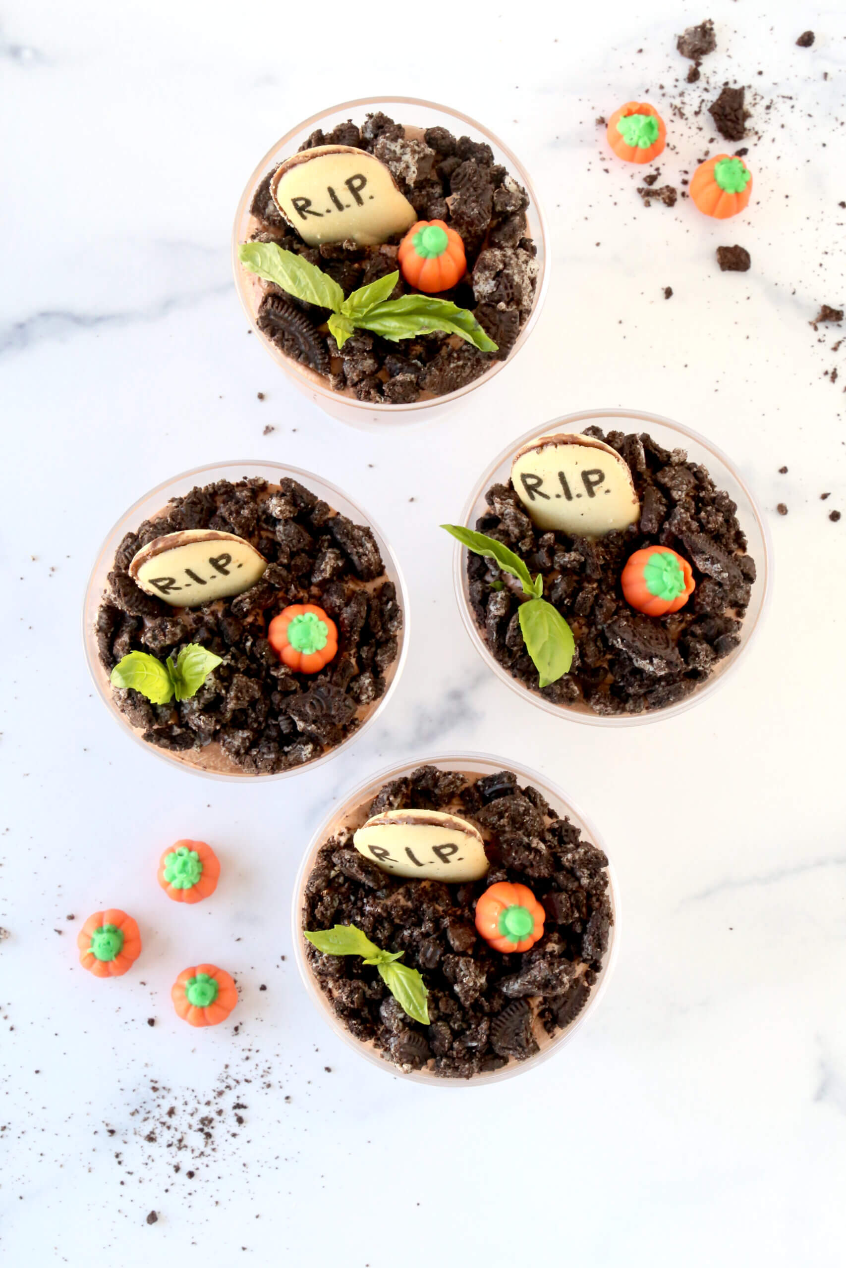 Four glass bowls filled with light brown chocolate mousse, topped with crushed oreos, fresh mint and a cookie that reads R.I.P.