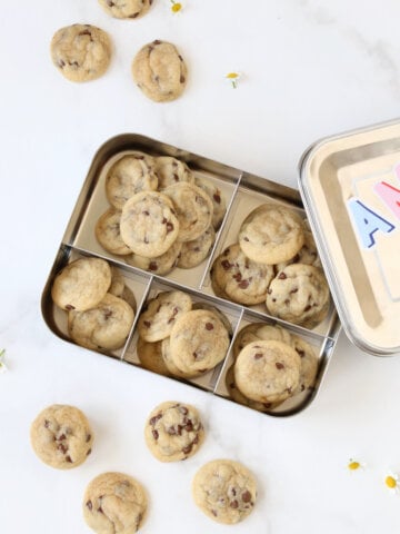 A metal lunch box filled with mini chocolate chip cookies.