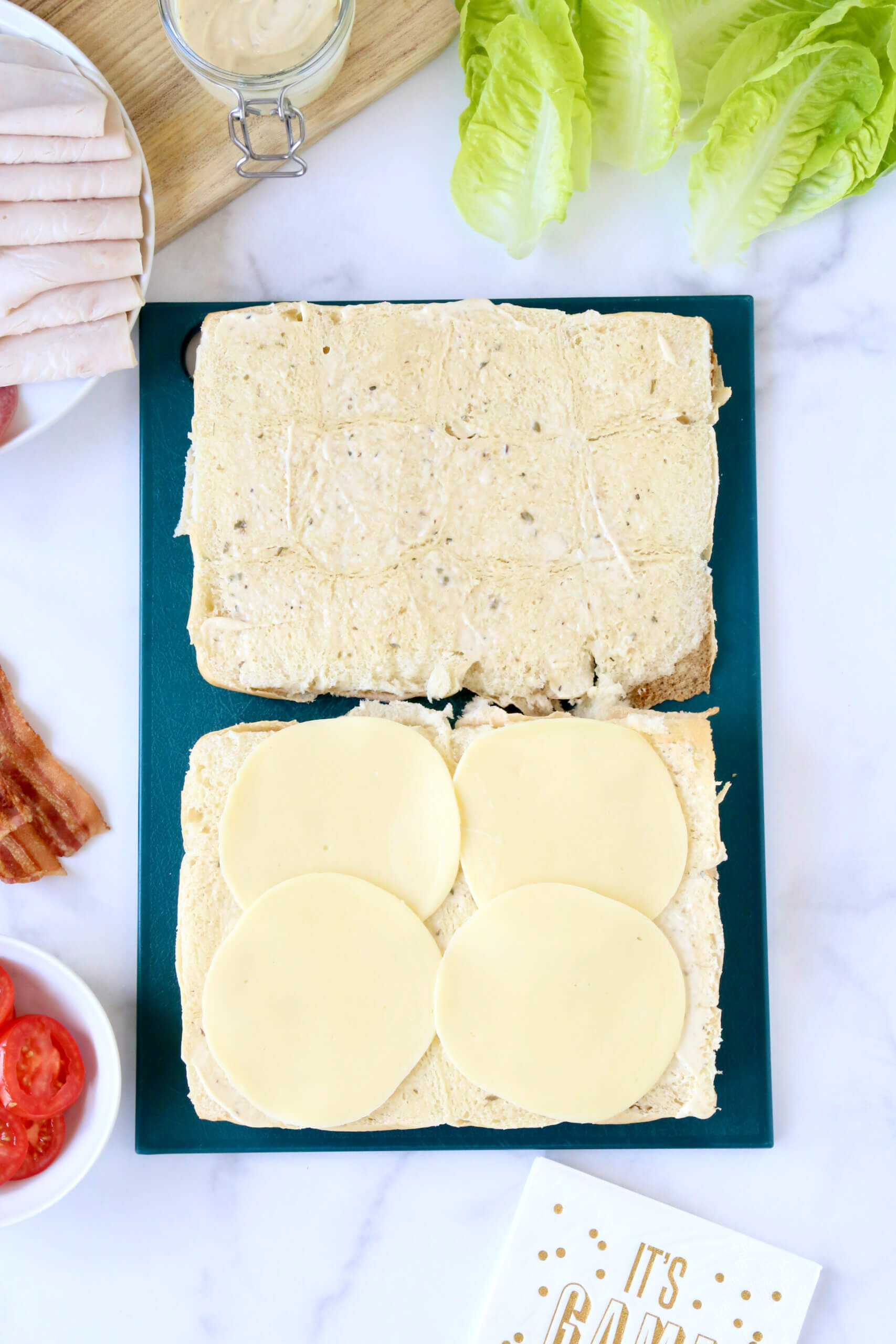 Sandwich bread sliced open and layered with four slices of round cheese. 