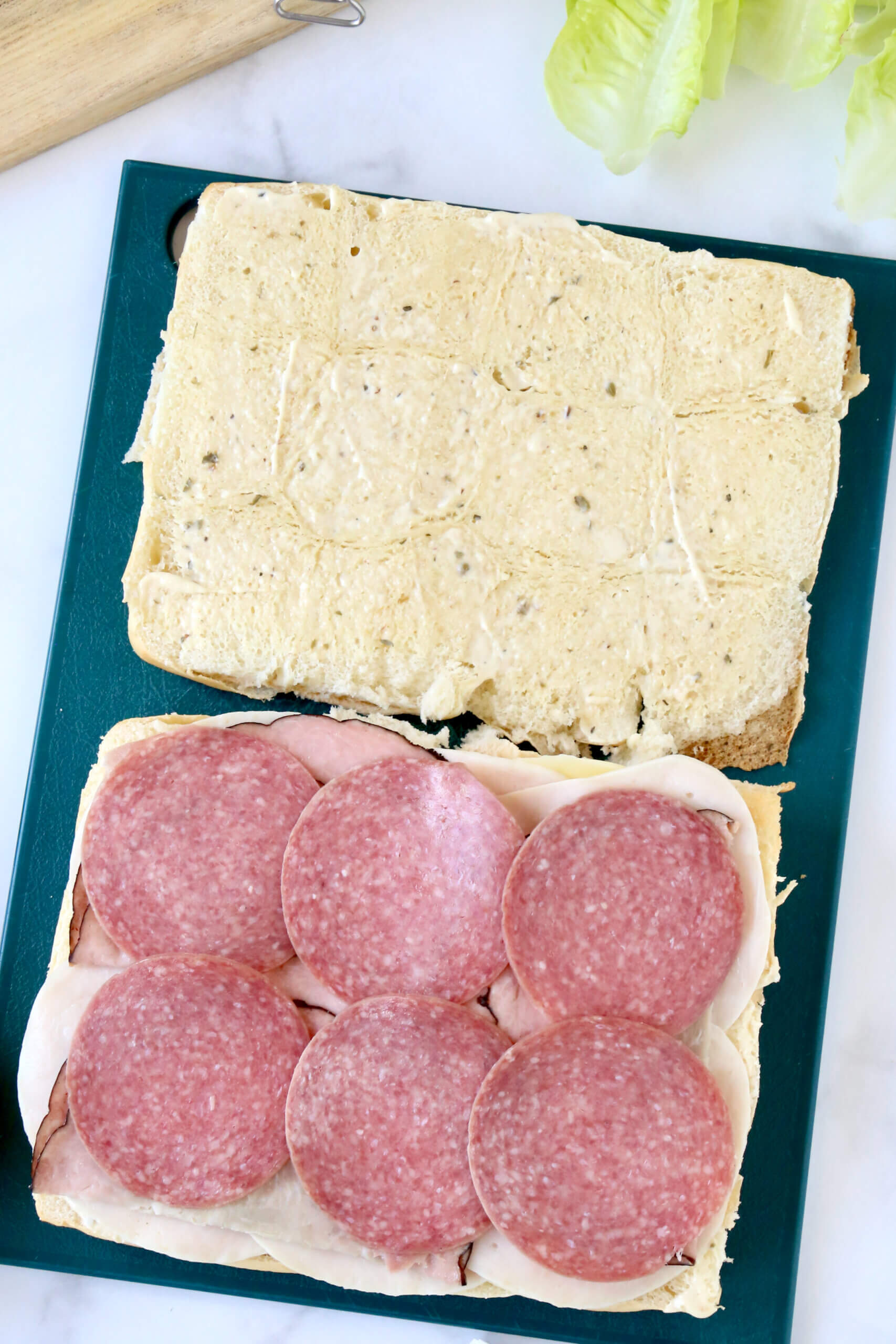 Sandwich bread sliced open and layered with six slices of salami.