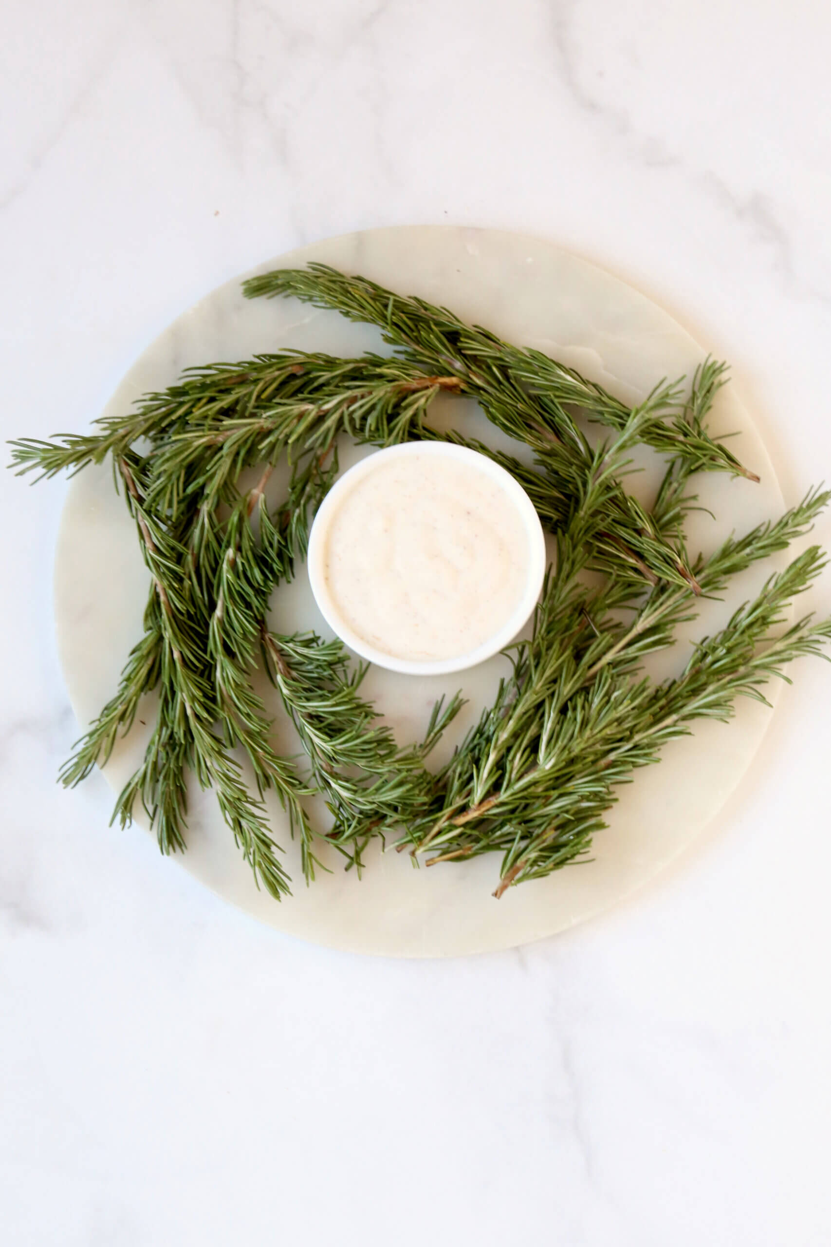 A round white platter topped with fresh rosemary sprigs.