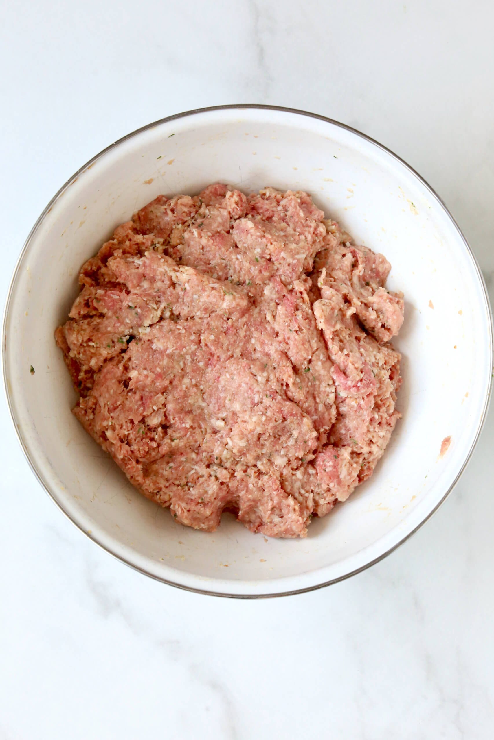 A white bowl filled with light pink raw meat.  