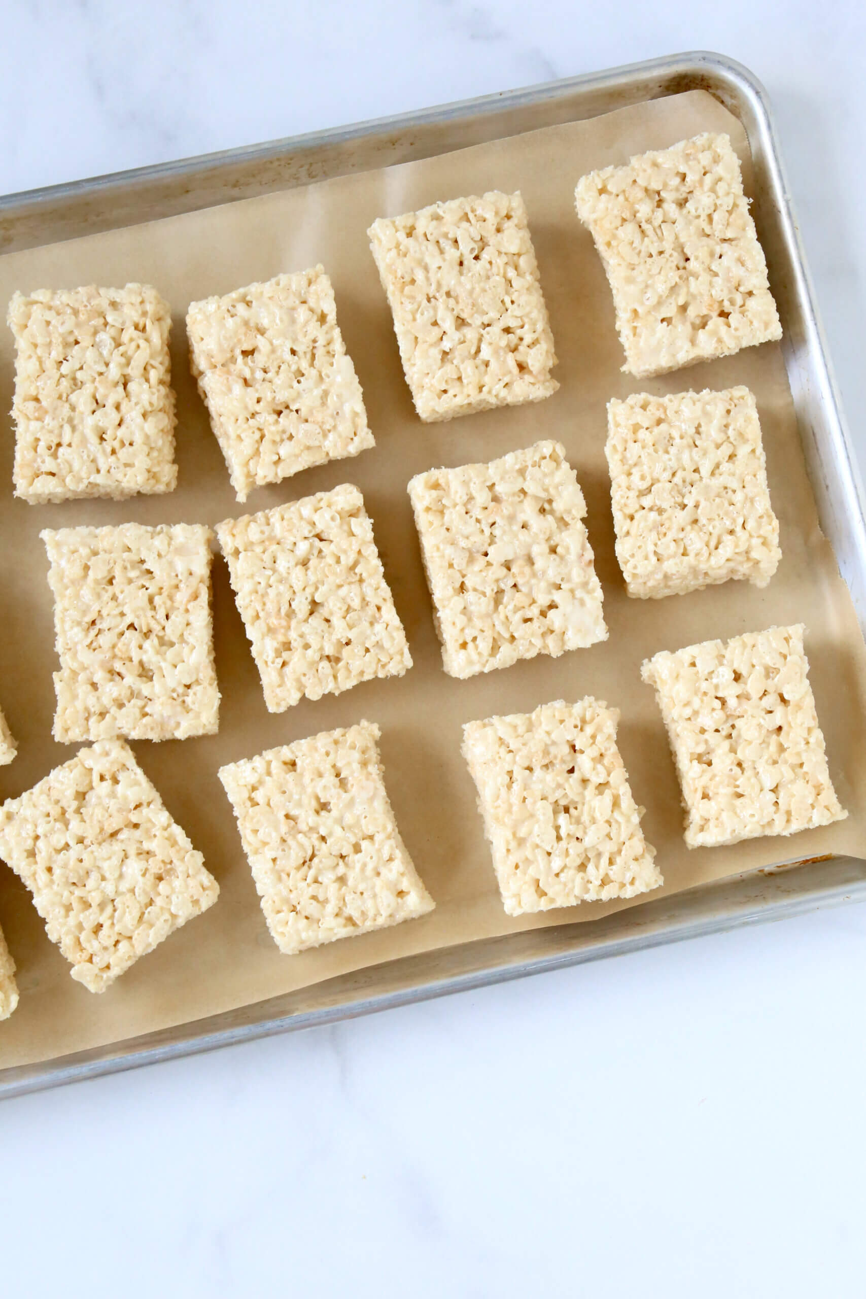 A gold tray with small rectangle squares of rice krispie treats.