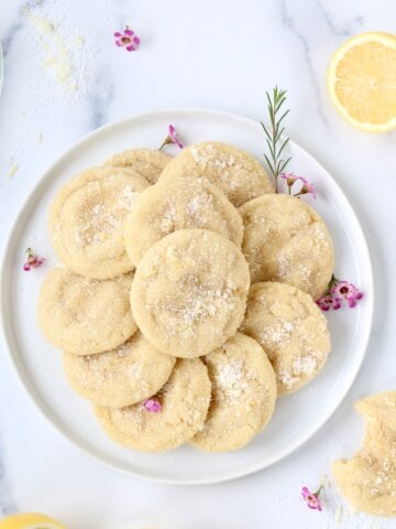 A white place with light yellow round cookies stacked on top.