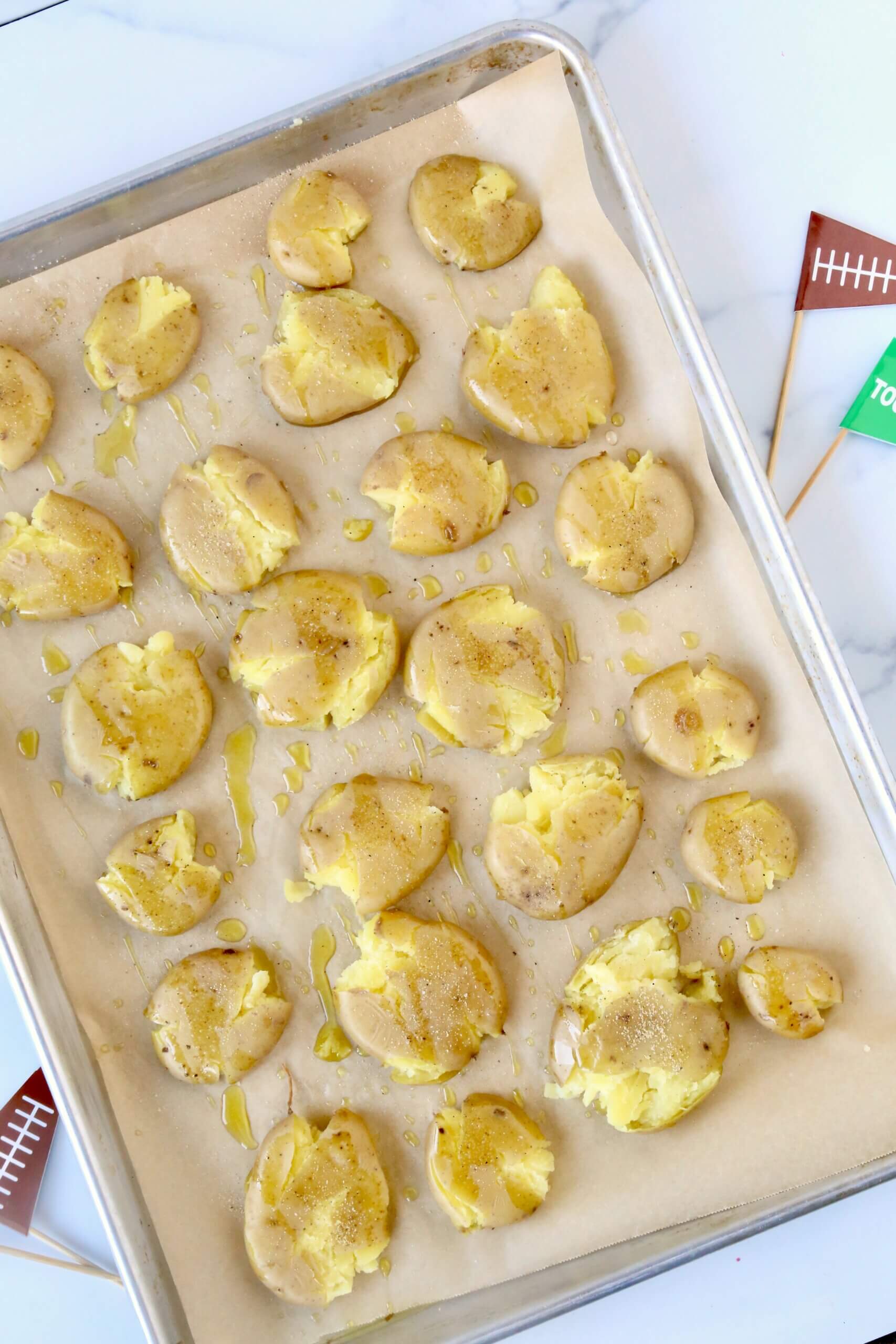 A silver pan topped with tan smashed golden yellow potatoes.
