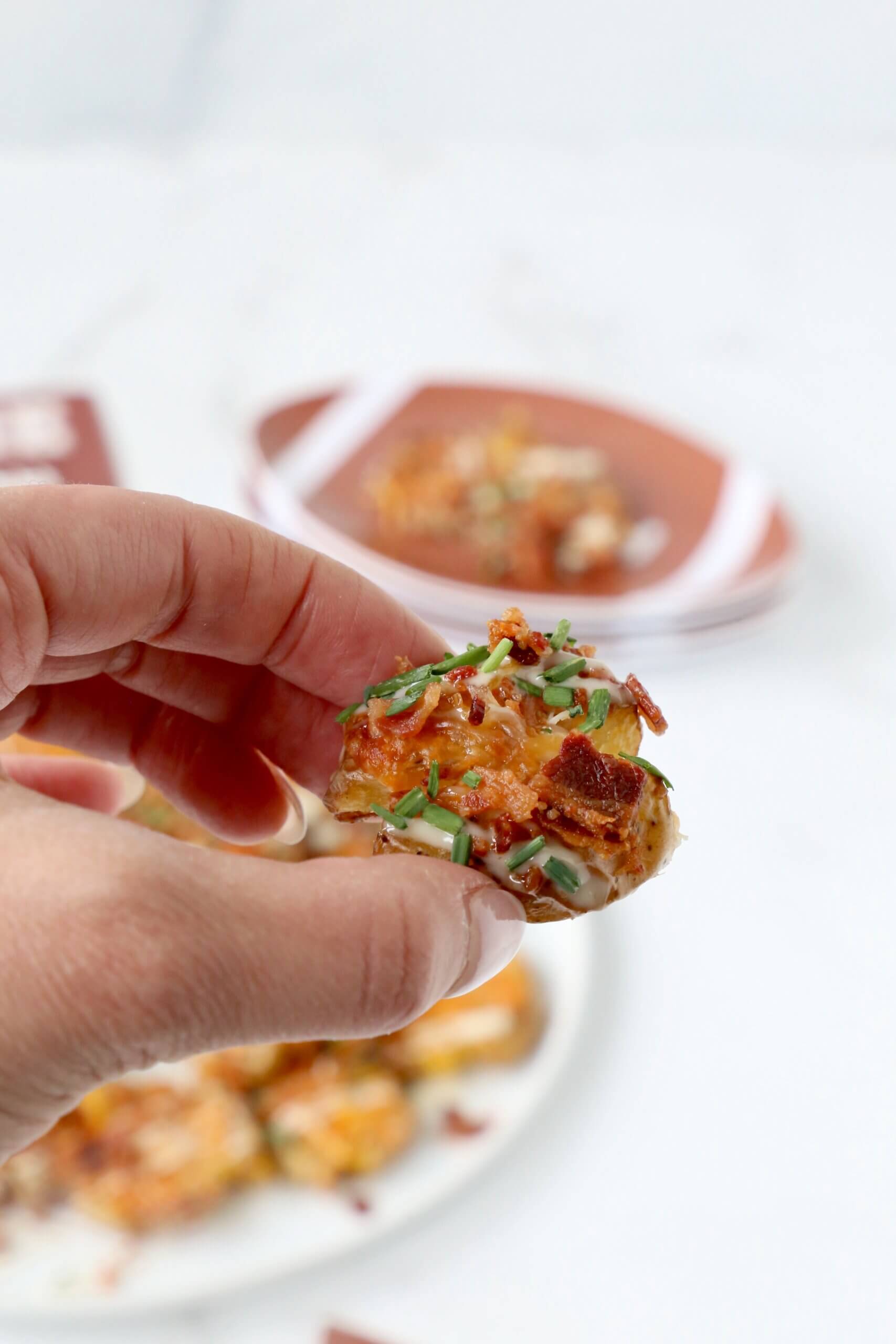 A hand holding one smashed potato.