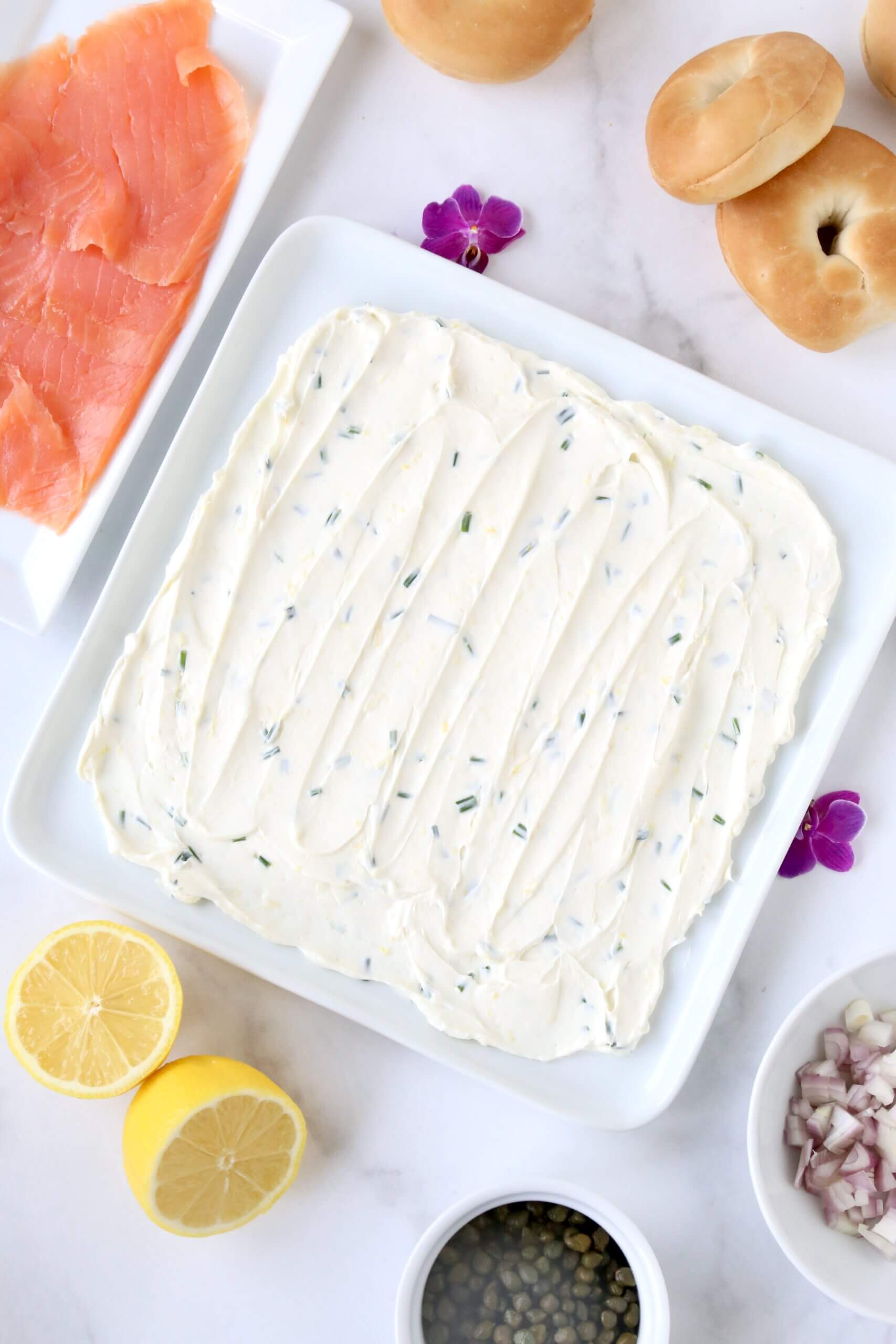 A white platter with a white cream cheese spread over the top.